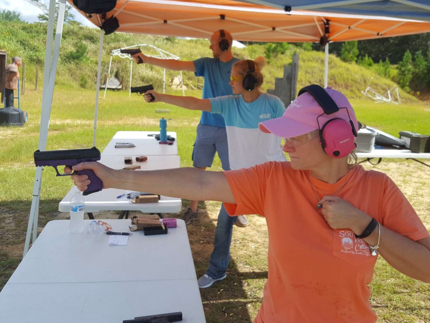A woman wearing an orange T-shirt practicing handgun