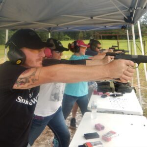 A person using a shotgun at a range park with others