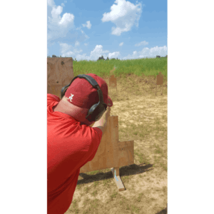 A man shooting wearing red T-shirt and a Cap